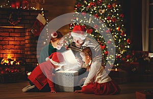 Merry Christmas! happy family mother father and children with magic gift near tree   at home