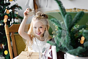 Merry Christmas and Happy Holidays. Cheerful cute child girl opening a Christmas present.