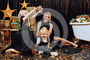 Merry Christmas and Happy Holidays! Cheerful and happy family with christmas gifts in golden packaging and dark background