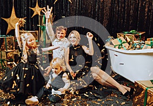 Merry Christmas and Happy Holidays! Cheerful and happy family with christmas gifts in golden packaging and dark background