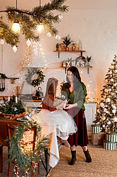 Merry Christmas and Happy Holidays. Cheerful mom and her cute daughter girl changing gifts. Parent and little child