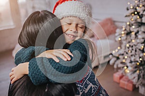 Merry Christmas and Happy Holidays Cheerful mom and her cute daughter girl exchanging gifts. Parent and little child