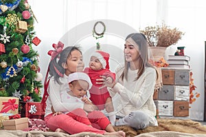 Merry Christmas and Happy Holidays! Cheerful mom and her cute daughters playing and have fun together