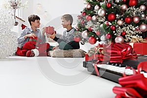 Merry christmas and happy holidays, children look at the gift packages near the christmas tree with musical instruments, at home