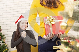 Merry Christmas and Happy Holidays. Christmas gift giving festival. Friend or sister giving Christmas present box indoors. Merry