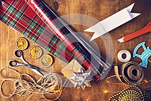 Merry Christmas and Happy Holidays! Christmas preparation, scissors, ribbons, stationery knife, sellotape on wood table
