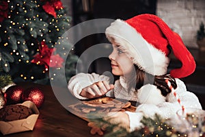 Merry Christmas and Happy Holidays. Cute child girl eating ginger cookies.