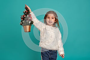 Merry Christmas and happy holidays. Cute little baby girl holding a Christmas tree. Christmas holiday concept
