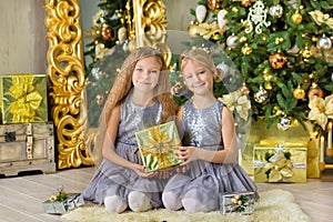 Merry Christmas and Happy Holidays Cute little child girls decorating the white green Christmas tree indoors with alot of presents