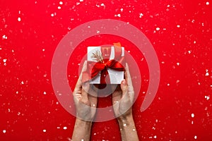 Merry Christmas and Happy Holidays greeting card, frame, banner. New Year. Noel. Hands holding gift box on red background