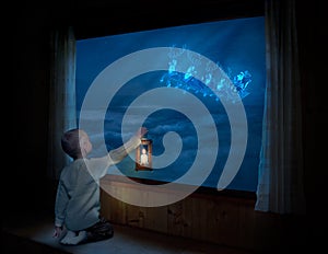 Merry Christmas and happy holidays! Little boy sitting on the window and looking at Santa Claus flying in his sleigh against moon