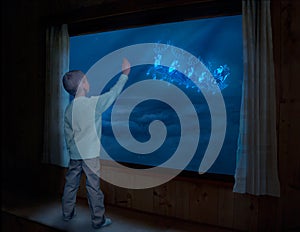 Merry Christmas and happy holidays!Little boy stands near the window and looks like Santa Claus flies in the sky in a sleigh with