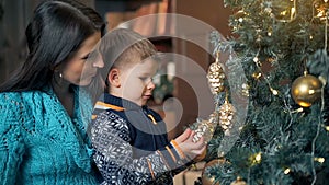 Merry Christmas and Happy Holidays. Mom and son decorating the Christmas tree indoors