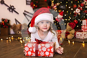 Merry Christmas and happy holidays. New Year 2020. Portrait of smiling cute little girl in red pajamas and Santa Claus hat holding