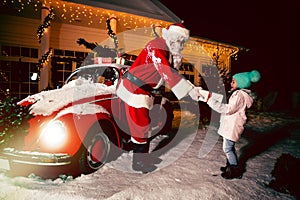 Merry Christmas and happy holidays! Santa Claus giving xmas presents cute little girl.