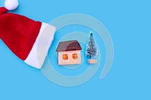 Merry Christmas and Happy Holidays,  Santa hat with house and fir tree on blue background