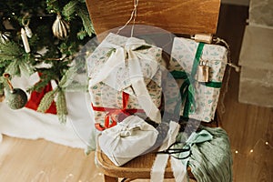 Merry Christmas and Happy Holidays! Stylish wrapped christmas gifts with ribbon on wooden old chair on background of decorated
