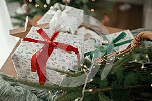 Merry Christmas and Happy holidays! Stylish wrapped christmas gifts, rustic basket with fir branches and modern decorations on