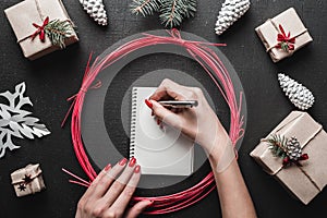 Merry Christmas and Happy Holidays! Woman hands with bright red nails writing letter with silver pen.