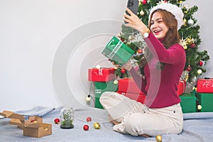 Merry Christmas and Happy Holidays! A young woman with a beautiful face in a red shirt shows joy with gift boxes in a house with a