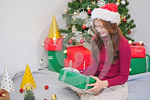 Merry Christmas and Happy Holidays! A young woman with a beautiful face in a red shirt shows joy with gift boxes in a house with a