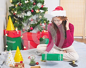 Merry Christmas and Happy Holidays! A young woman with a beautiful face in a red shirt shows joy with gift boxes in a house with a