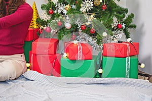 Merry Christmas and Happy Holidays! Young woman with a beautiful face in a red shirt shows joy with gift boxes in a house with a