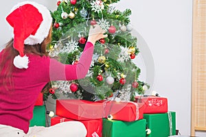 Merry Christmas and Happy Holidays! Young woman with a beautiful face in a red shirt shows joy with gift boxes in a house with a