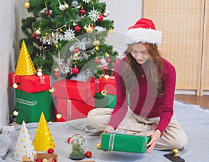 Merry Christmas and Happy Holidays! Young woman with a beautiful face in a red shirt shows joy with gift boxes in a house with a