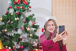 Merry Christmas and Happy Holidays! Young woman with a beautiful face in a red shirt shows joy with gift boxes in a house with a