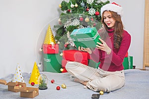 Merry Christmas and Happy Holidays! Young woman with a beautiful face in a red shirt shows joy with gift boxes in a house with a