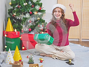 Merry Christmas and Happy Holidays! Young woman with a beautiful face in a red shirt shows joy with gift boxes in a house with a