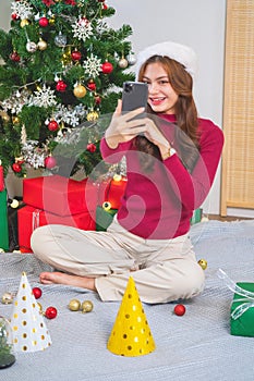 Merry Christmas and Happy Holidays! Young woman with a beautiful face in a red shirt shows joy with gift boxes in a house with a