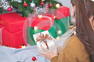 Merry Christmas and Happy Holidays! Young woman with a beautiful face in a yellow shirt shows joy with gift boxes in a house with