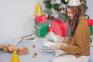 Merry Christmas and Happy Holidays! Young woman with a beautiful face in a yellow shirt shows joy with gift boxes in a house with