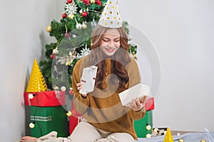 Merry Christmas and Happy Holidays! Young woman with a beautiful face in a yellow shirt shows joy with gift boxes in a house with