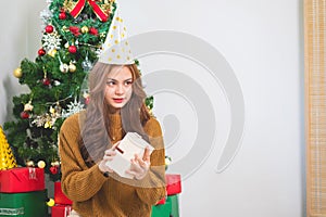 Merry Christmas and Happy Holidays! Young woman with a beautiful face in a yellow shirt shows joy with gift boxes in a house with