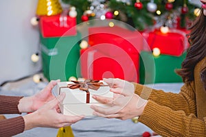 Merry Christmas and Happy Holidays! Young woman with a beautiful face in a yellow shirt shows joy with gift boxes in a house with