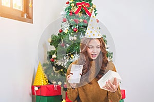 Merry Christmas and Happy Holidays! Young woman with a beautiful face in a yellow shirt shows joy with gift boxes in a house with