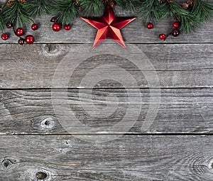 Merry Christmas or happy New Year background with fir tip branches and red star decoration on rustic wood