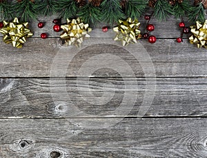 Merry Christmas or happy New Year background with fir tip tree branches and gold bows on rustic wood