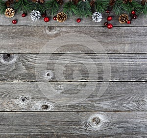 Merry Christmas or happy New Year background with fir tip tree branches and gold silver pine cones on rustic wood