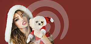 Merry Christmas. Happy New Year. Beautiful Christmas woman in fur hat with Pomeranian Spitz doggy in Xmas clothing and