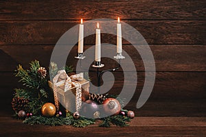 Merry Christmas and Happy New Year! Candelabra with three candles, boxes with gifts, Christmas balls and fir branches on a wooden