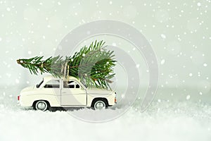 Merry Christmas Happy New Year concept. Retro toy car with christmas tree on snowy winter background. Copy space for your text