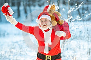 Merry Christmas and Happy New Year concept. Santa Claus pulling huge bag of gifts on white nature background.