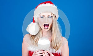 Merry Christmas and Happy New year. Cute girl in Santa hat with Christmas ball. Winter holidays, Christmas and New Year