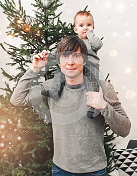 Merry Christmas and Happy New Year! Father and son smiling in living room decorated by christmas tree and xmas gift boxes.