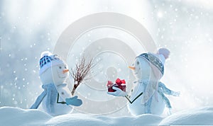 Merry Christmas and happy New Year greeting card with copy-space. Snow background. Two cheerful friends snowmen standing in winter
