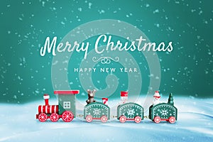 Merry Christmas and Happy New Year greeting card with cute train toy on snow with green background